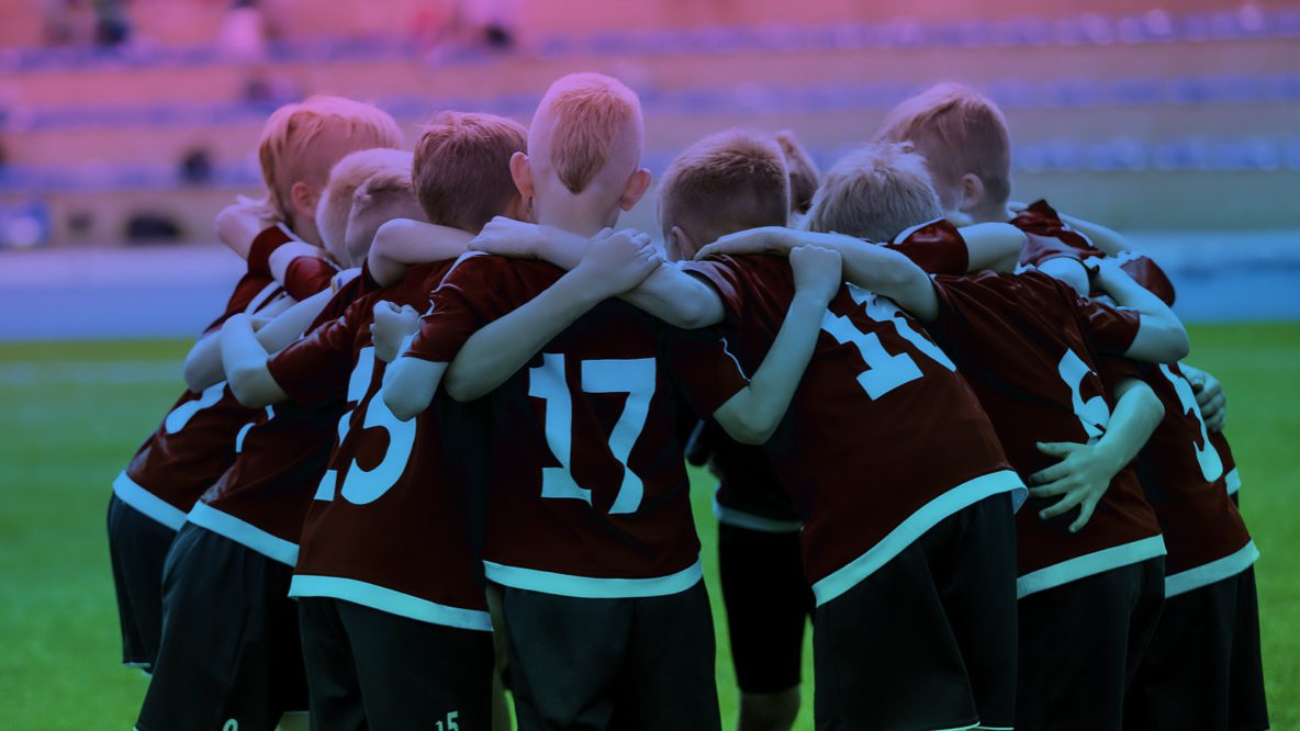 A group of children wearing sports attire hugging at a sports event