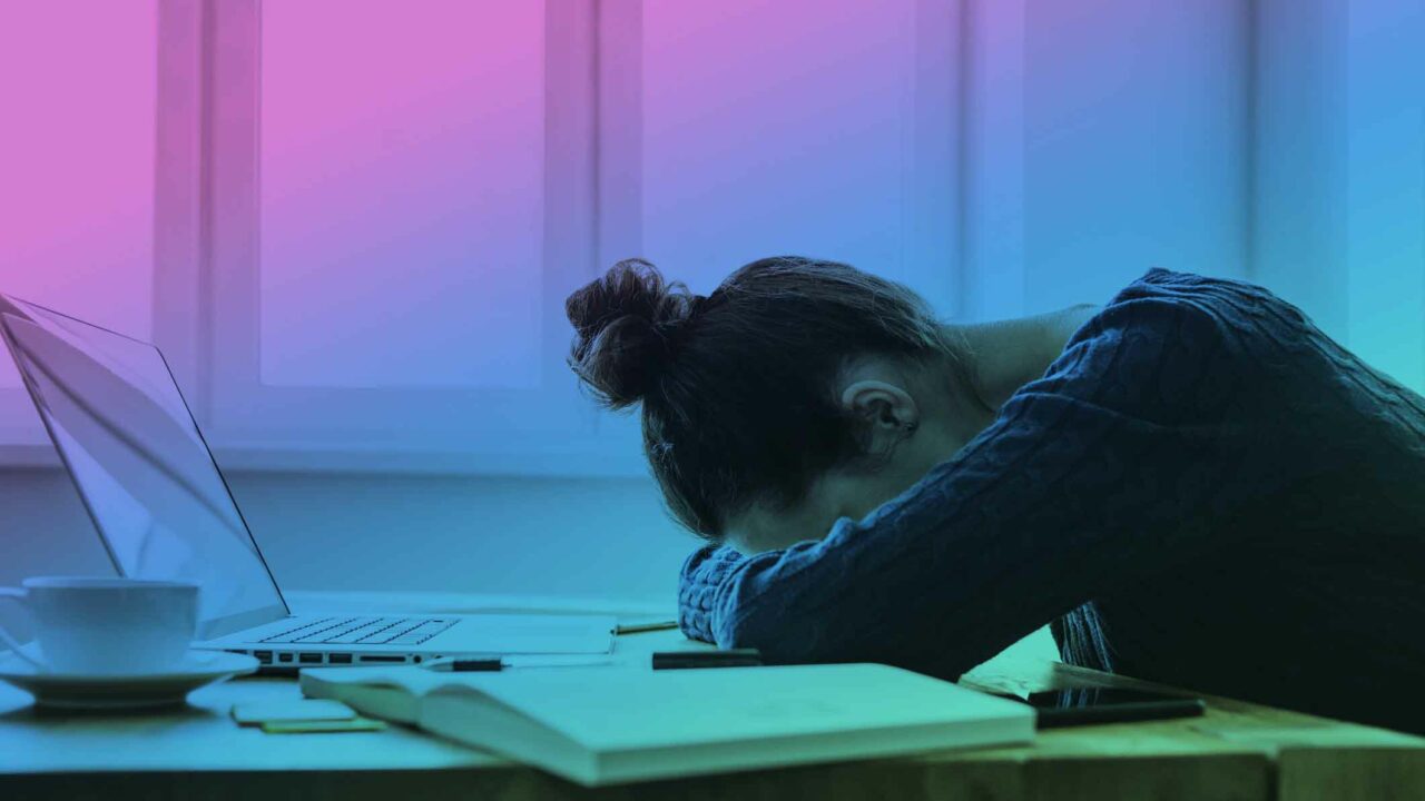 Woman with her head on the desk suffering from post-concussion fatigue